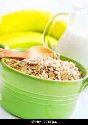 Fiocchi di avena nel verde ciotola con banana e latte Foto Stock