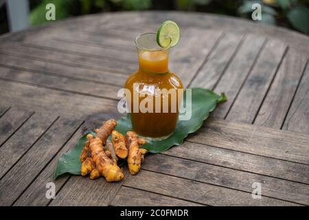 curcuma con foglie curcuma ed erbe curcuma in bottiglie di vetro sul tavolo di legno Foto Stock