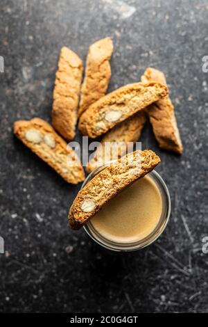 Biscotti dolci alla cantuccina. Biscotti alle mandorle e tazza di caffè su tavola nera. Vista dall'alto. Foto Stock