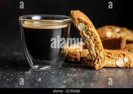 Biscotti dolci alla cantuccina. Biscotti alle mandorle e tazza di caffè su tavola nera. Foto Stock