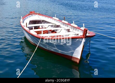 Battello a remi in legno rosso e bianco che galleggia sul mare in un porto. Galizia, Spagna. Foto Stock