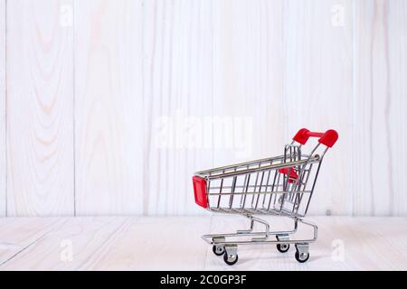 Carrello spesa contro il bianco sullo sfondo di legno Foto Stock