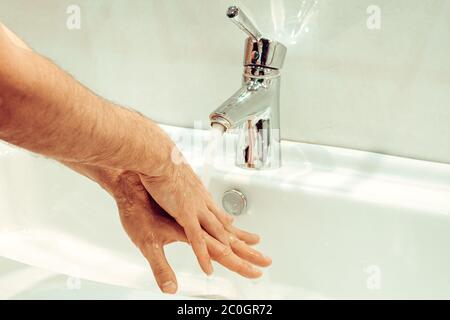 Primo piano di un giovane uomo caucasico che si lava le mani con sapone nel lavello del bagno igiene personale, protezione contro virus e batteri concetto Foto Stock