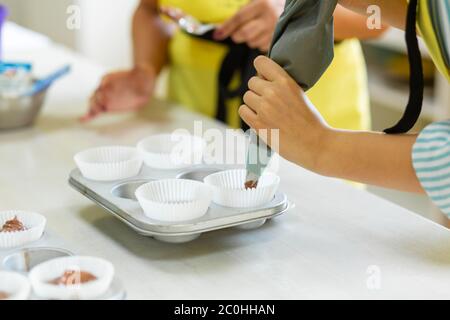 Donna chef professionista pasta spalmare pasta di cioccolato in piatto da forno. Foto Stock