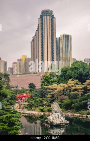 Splendido contrasto tra alberi verdi e fiori in fiore e alti edifici residenziali nel Giardino Nan Lian di Hong Kong Cina Foto Stock