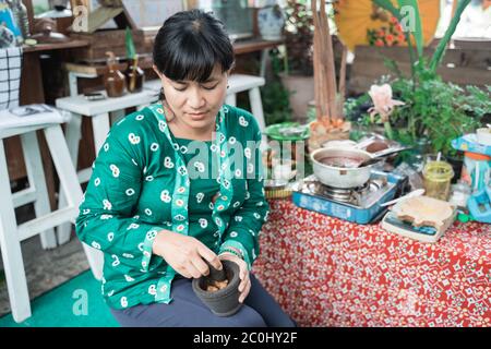 donna che vende masse di medicina di erbe usando mortaio, il concetto di concocting medicina di erbe tradizionale Foto Stock