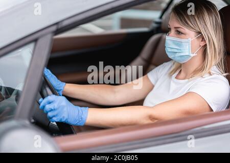 Giovane donna che guida l'auto mentre indossa la maschera di sicurezza per la prevenzione della diffusione del coronavirus - nuove regole di stile di vita dopo l'epidemia di Covid-19 - Salute a Foto Stock