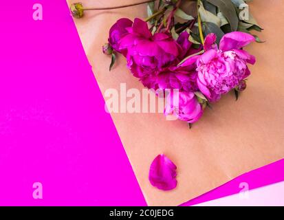 Bouquet di peonie rosa fresche su sfondo rosa avvolto in carta marrone. Consegna fiori. Foto Stock