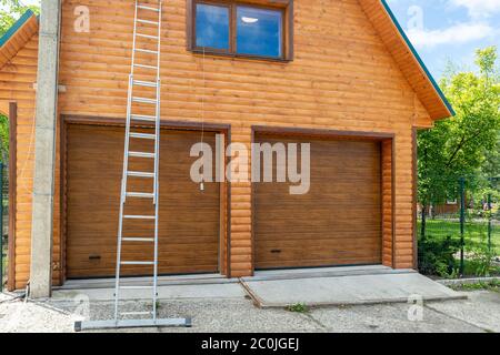 Nuovo garage moderno per due auto cantiere taglio finale con parete in legno. Scala professionale in alluminio estesa alta su Foto Stock