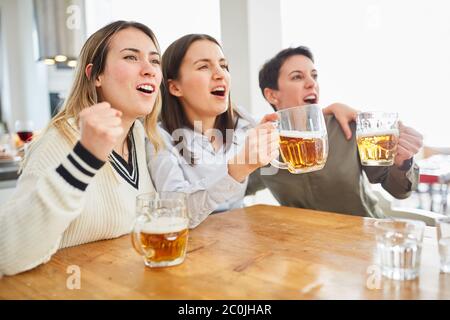 Gruppo di donne guarda il calcio e beve birra e brilla nella loro squadra Foto Stock