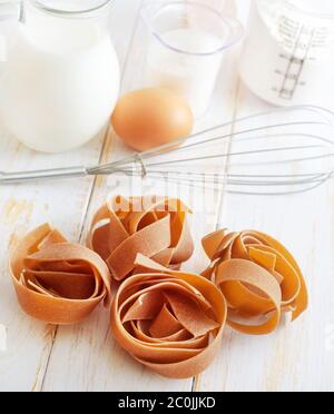La pasta grezza sul tavolo bianco, gli ingredienti per la pasta Foto Stock