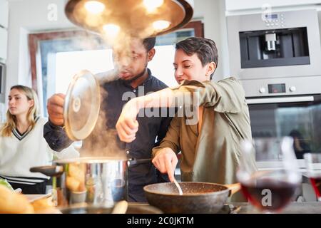 Gli amici cucinano la pasta con salsa in cucina condivisa per un pasto condiviso Foto Stock