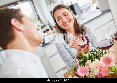 Giovane donna felice riceve bouquet e anello di nozze per la proposta di matrimonio a casa Foto Stock