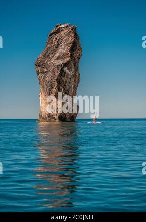 Stand up paddle boarding. Pratica forte di un uomo su una scheda SUP. L'avventura del mare con l'acqua blu su un surf. Il concetto di un attivo e guarire Foto Stock