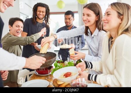 Gruppo di vegani che mangiano nella cucina in comune, spaghetti e contorno Foto Stock