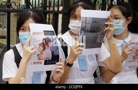 Hong Kong, CINA. 12 giugno 2020. Le studentesse di HEUNG ALLA SCUOLA MEDIA, una 'scuola di sinistra' tradizionalmente pro-Pechino, mostrano un piccolo poster fuori dalla facoltà durante una dimostrazione politica. Sul poster è scritto : IL CROLLO DI HONG KONG EDUCATION.June-12, 2020 Hong Kong.ZUMA/Liau Chung-ren Credit: Liau Chung-ren/ZUMA Wire/Alamy Live News Foto Stock