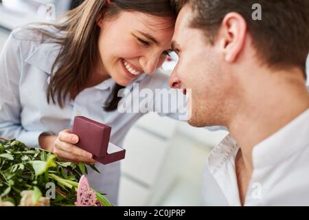 Felice donna che tiene scatola con anello di impegno dopo la richiesta di uomo il giorno di San Valentino Foto Stock