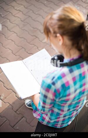 Studente ragazza con copybook sul banco di lavoro. Campus estivo di parco. Foto Stock