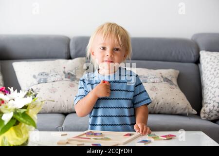 Piccolo bambino che fa puzzle. Ragazzo imparare di base sviluppare le abilità cognitive, concetto di bambino Foto Stock