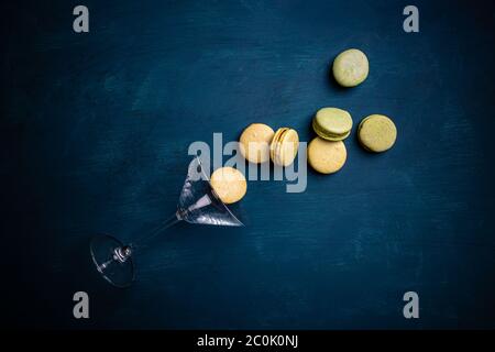 Studio di foto di macaron fuoriuscito dal vetro di martini, vista dall'alto, sfondo blu Foto Stock