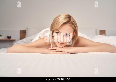 Sorridente bella signora rilassante in una camera da letto Foto Stock