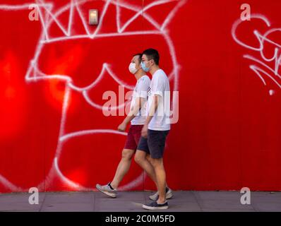 2 pedoni che camminano indossando maschere di protezione durante la crisi del Covid 19 Foto Stock