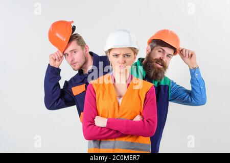 Donna, leader in cappello duro con faccia seria in piedi davanti ai costruttori. Concetto di Lady boss. Team di architetti, costruttori, operai che si alleano dietro donna isolato sfondo bianco. Foto Stock