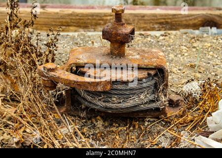 Vecchio verricello arrugginito con meccanismo a cricchetto e nottolino e cavo in acciaio arrotolato all'interno Foto Stock