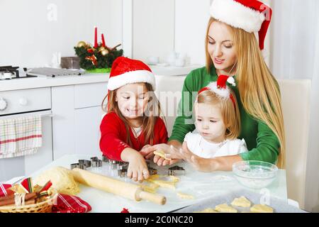 Due bambine e madre che cucinano i biscotti di Natale in cucina Foto Stock