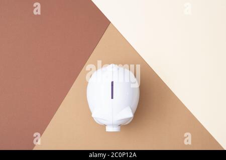 Bianco piggy bank visto dall'alto con uno sfondo marrone fatto da cartoncino Foto Stock