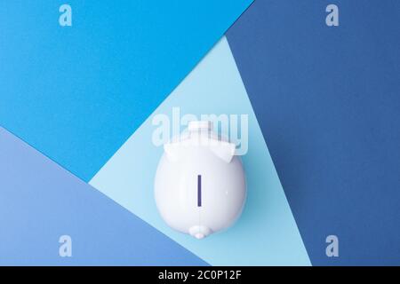 Bianco piggy bank visto dall'alto con uno sfondo fresco colorato fatto da cartoncino Foto Stock