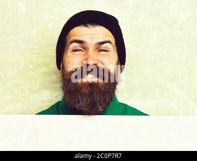Uomo Barbuto in cappuccio nero, barba lunga e brutali caucasian hipster con baffi getting barba taglio di capelli dal parrucchiere al barbiere con felice faccia sorridente sul verde studio sullo sfondo della parete Foto Stock