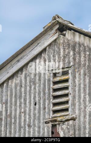 Bocca di fienile in legno sfinestrata in fattoria outbuilding gable end. Metafora circolazione d'aria, ventilazione, doghe di legno. Foto Stock