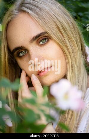 ragazza bella bionda felice con fiori guardando la macchina fotografica Foto Stock