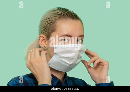 giovane donna in maschera di protezione medica guardando la fotocamera su sfondo verde Foto Stock