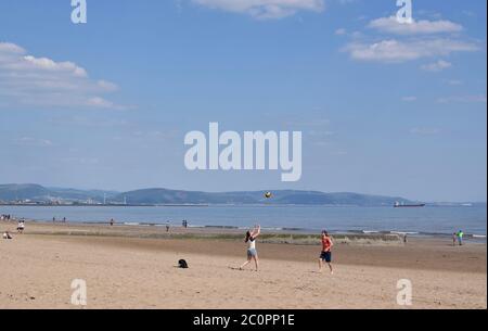 La giovane coppia gioca con la palla sulla spiaggia di sabbia in una bella giornata. Foto Stock