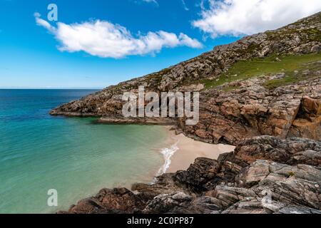 ACHMELVICH BAY E BEACH SUTHERLAND HIGHLANDS SCOZIA UNA PICCOLA COVE CON CIELO BLU I COLORI DEL MARE E DELLE ROCCE DI COLORE ARANCIONE Foto Stock