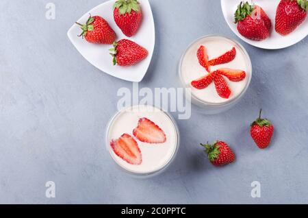 Dessert di fragole in un vaso di vetro con fragole fresche su un tavolo grigio Foto Stock