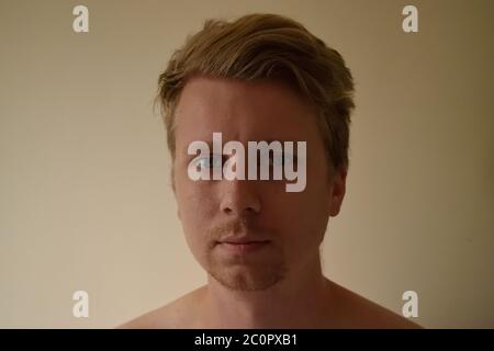 Ritratto di un giovane uomo a metà degli anni 20 che guarda la fotocamera con espressione neutra Foto Stock