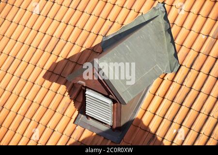 Primo piano di una piccola bocchetta sul tetto in tegole rosse. Giorno di sole. Foto Stock