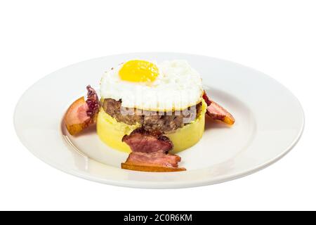 colazione a base di omme. uova fritte e polpettine di carne sulla patata fritta, decorata con pancetta. cibo isolato su sfondo bianco. vista laterale Foto Stock