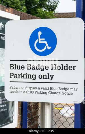 Cartello blu con badge solo per il parcheggio presso una stazione ferroviaria, posti auto per i conducenti disabili, Regno Unito Foto Stock