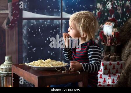 Dolce bambino, ragazzo, mangiando gli spaghetti a casa a Natale Foto Stock