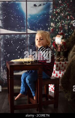 Dolce bambino, ragazzo, mangiando gli spaghetti a casa a Natale Foto Stock