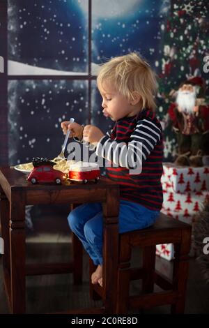 Dolce bambino, ragazzo, mangiando gli spaghetti a casa a Natale Foto Stock