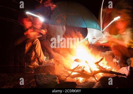 Gli escursionisti si sono riuniti intorno a un falò di notte con una lunga esposizione shot Foto Stock