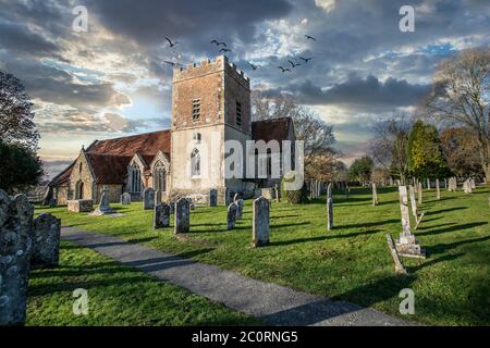 Chiesa di campagna inglese e cimitero, con un cielo interessante e lapidi Foto Stock