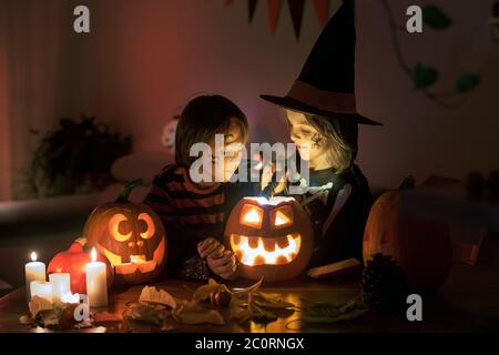 Bambini, fratelli ragazzi, giocando con zucca scolpita a casa su Halloween, facendo pozione magica Foto Stock