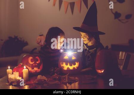 Bambini, fratelli ragazzi, giocando con zucca scolpita a casa su Halloween, facendo pozione magica Foto Stock