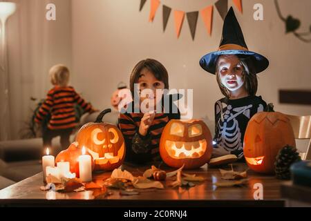 Bambini, fratelli ragazzi, giocando con zucca scolpita a casa su Halloween, facendo pozione magica Foto Stock